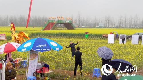 游客在油菜花海中拍照